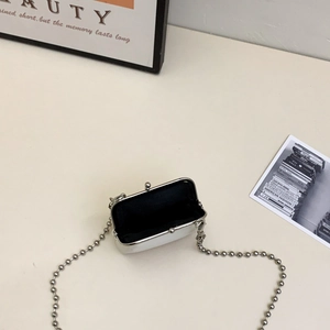 Overhead view of white matte leather mini kiss-lock bag with silver chain strap