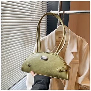 Close-up of light green crocodile pattern handbag with metal plate and dual slim straps