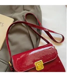 Close-up of a retro red patent leather bag featuring a polished gold rectangular metal lock