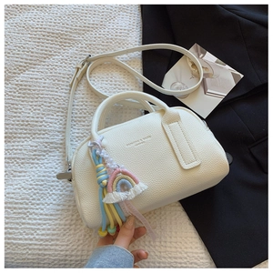 Detail of white lychee leather Boston bag with rainbow charm and fashion embossed text