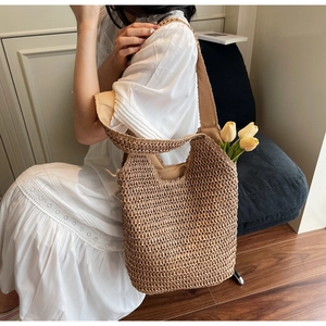 Detail of hollow-out hand-woven straw tote bag with wide shoulder strap in khaki