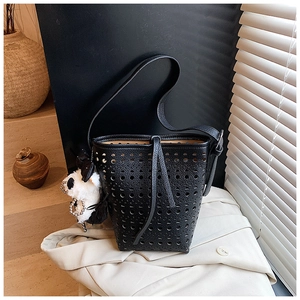 Détail du sac seau en cuir noir ajouré avec motifs découpés et pendentif peluche