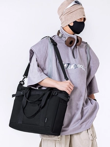 Black high-capacity nylon tote bag with wide crossbody strap and utility details