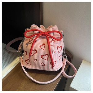 Détail du sac seau en velours côtelé rose avec broderies cœurs rouges et grand nœud serrage