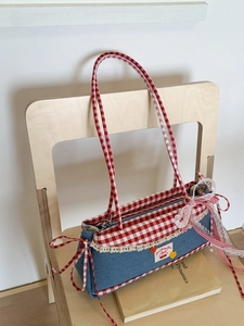 Blue denim baguette bag with red gingham trim and white lace ruffles on a wooden chair