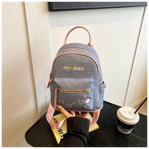 Close-up of contrast denim backpack with pink straps and colorful cute embroidery