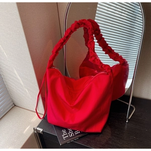 Red pleated nylon tote bag detail with cloud-style handle and minimalist design
