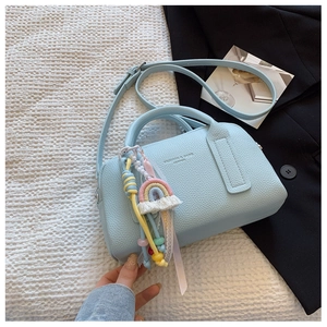Detail of light blue pebble leather handbag featuring a colorful rainbow charm and strap