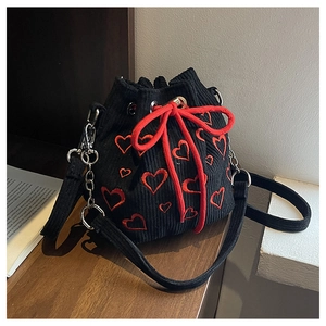 Détail du sac seau en velours côtelé noir avec broderie cœur rouge et cordon coulissant