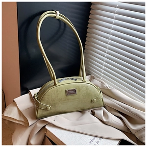 Detail of avocado green crocodile embossed handbag with metal logo on chic beige blazer