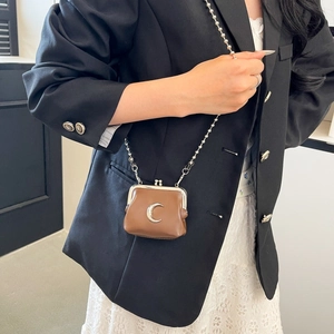Detailed view of mini brown leather crossbody bag with silver moon detail on black blazer