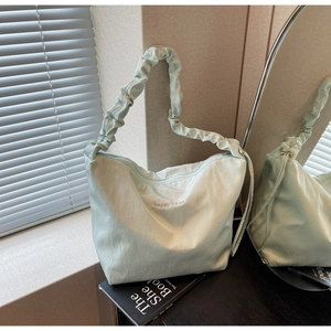 Detail of mint green canvas tote bag featuring pleated strap and happy vibes embroidery