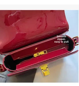 Detail of red patent leather handbag featuring smooth gold zipper and luxury clasp closure
