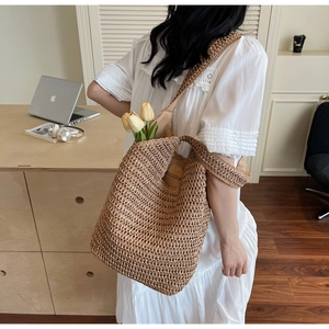 Detail of hand-woven straw beach bag featuring hollow texture and yellow tulip decoration