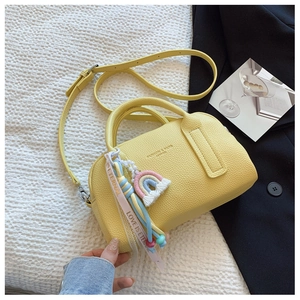 Detail of yellow boston pillow bag with rainbow pendant and adjustable shoulder strap