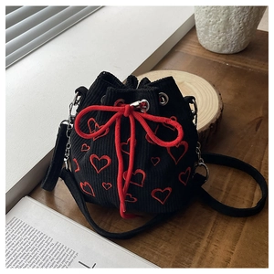 Détail du sac seau en velours côtelé noir avec broderie cœur rouge et cordon