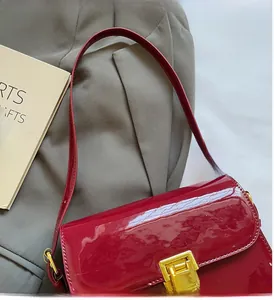 Detail of red patent leather shoulder bag with golden metallic lock on blazer background