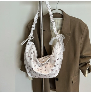 Detail of white floral oxford bag with scrunchie strap and lace bow accent