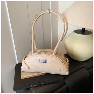 Detail of beige crocodile pattern handbag featuring silver logo and dual zippers