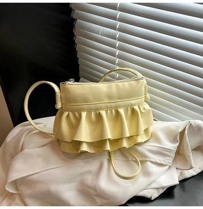 Detail of a light yellow ballet-style shoulder bag with elegant ruffled folds and PU leather