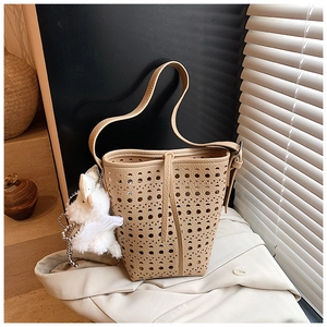 Gros plan du sac seau ajouré en cuir avec un joli pendentif d'animal en peluche