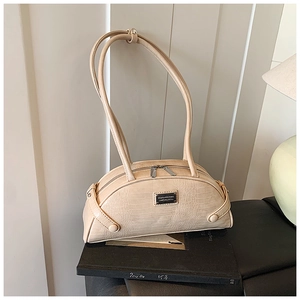 Detail of light beige crocodile texture handbag with silver zipper and metal logo tag