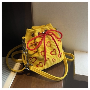 Détail du sac seau en velours côtelé jaune avec broderies de cœurs rouges et cordon