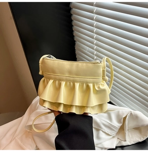 Detailed view of yellow crossbody bag featuring tiered ruffle design and smooth finish