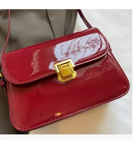 Detail of red patent leather shoulder bag with golden metallic rectangular buckle closure