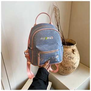 Close-up of denim backpack featuring heart embroidery and contrast pink straps