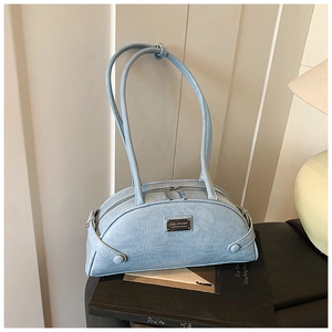 Detail of light blue crocodile-embossed pillow bag with double straps and metal zipper