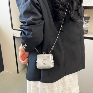 Silver mini crossbody bag with metal moon clasp worn over a black blazer and lace dress