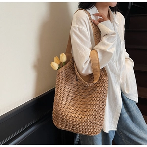 Detail of hand-woven straw tote bag with wide fabric strap and large capacity