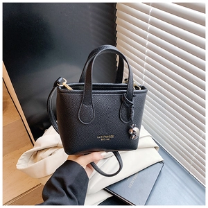 Dettaglio della mini borsa a secchiello nera con logo dorato e pendente in metallo