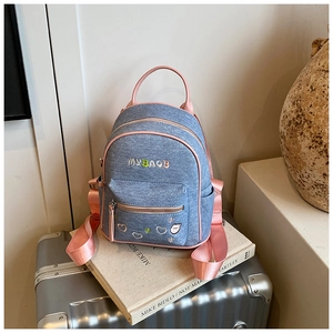 Detail of mini denim backpack with pink trim and cute cartoon heart embroidery