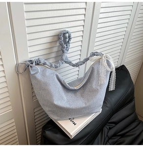 Detailed shot of blue striped canvas bag with white lace bow and pleated shoulder strap