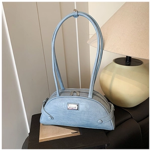 Detail of light blue crocodile embossed handbag with double zipper and metal logo plate