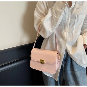 Close-up of light pink patent leather shoulder bag with glossy finish and gold clasp