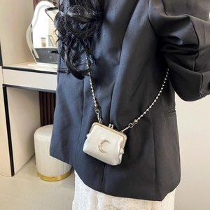 Back view of model wearing a mini silver chain bag with moon metal detail over black blazer