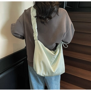 Detailed view of mint green tote bag featuring cloud pleated strap and happy day embroidery