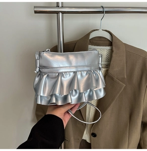 Close-up of a mini silver metallic bag featuring double-layered ruffled pleats and zipper detail