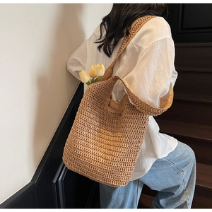 Detail of a large handmade straw beach tote bag with tulips on a staircase background