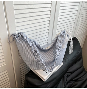 Detail of blue striped crescent bag with elegant lace bow and ruffle edge texture