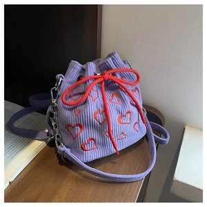 Vue détaillée du sac seau en velours violet avec cœurs brodés et cordon rouge