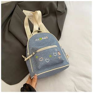Detail of light blue denim mini backpack featuring MY BAG colorful embroidery and heart motifs