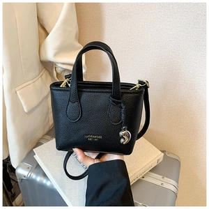 Dettaglio mini borsa a secchiello nera con trama in pelle e ciondolo a cuore in metallo