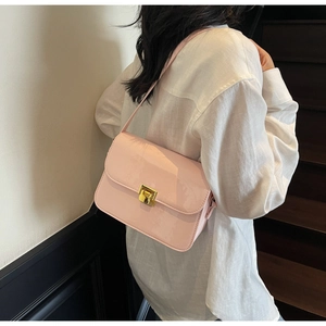 Close-up of pink patent leather crossbody bag with a sleek gold rectangular clasp