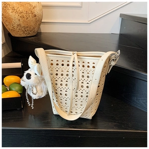 Détail du sac seau blanc cassé avec découpes géométriques et texture cuir de lychee