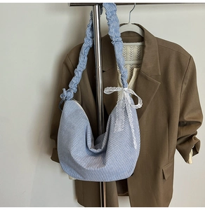 Detail of blue and white striped hobo bag with a white lace bow and ruffled strap