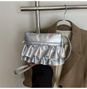 Detailed view of silver metallic crossbody bag with double-layered ruffle design and zipper